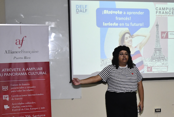 La estudiante Naujelee Ortiz Berríos, tesorera del Cercle Francophone, en el escenario dando la bienvenida al evento.