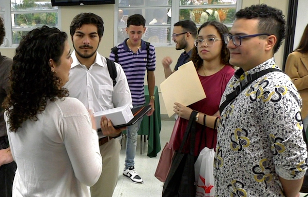 Grupo de estudiantes conversa con una de las reclutadoras en la Feria de empleos de Administración de Empresas.