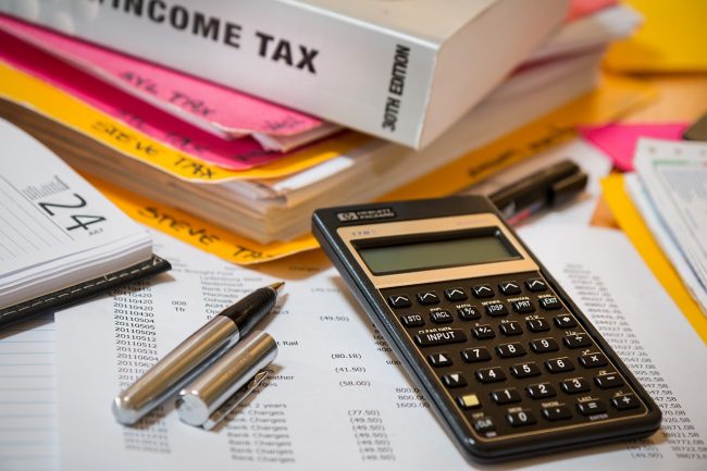 income-tax-4097292_1280 Imagen que muestra una calculadora, bolígrafo, libros, calendario y documentos relacionados con la planilla de contribuciones.