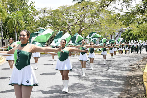 Foto de las Abanderadas al frente de la Banda de Marcha haciendo una figura durante el desfile por el campus.