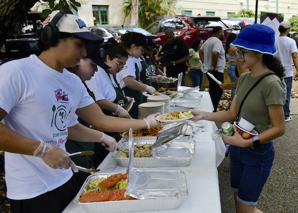 Portadita Integrantes de Come Colegial reparten almuerzos a una estudiante en la Plazita Chardón.