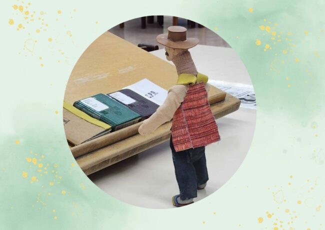 Marioneta del proyecto RUManimadas frente a varios libros.