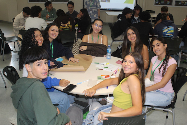 Participantes del campamento de verano de Empresas en el Colegio, sentados en una mesa durante uno de los talleres.