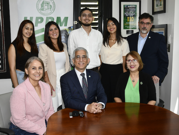 Los cuatro estudiantes que representan este verano al RUM en programas de internado de SUNY, junto a los decanos y el rector durante el anuncio de su representación en Nueva York. Algunos de pie y otros sentados en la mesa de reuniones de la Oficina del Rector.