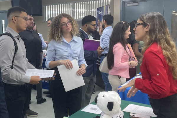 Una reclutadora conversa con dos estudiantes durante la feria de empleos del Colegio de Administración de Empresas en el RUM.