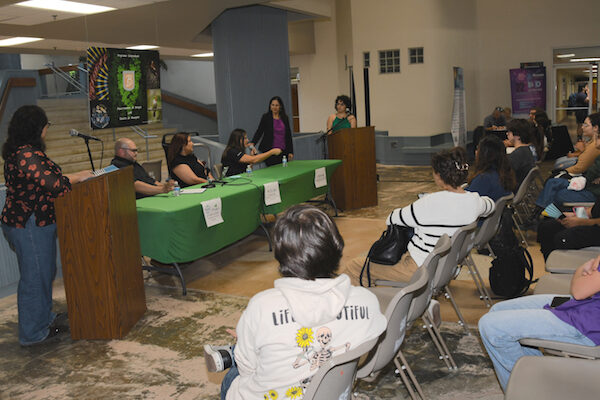 Portada La doctora Yadira Malavez Acevedo, junto a una estudiante en el podio, durante la sesión de preguntas a los panelistas de la industria, quienes están sentados en una mesa en el vestíbulo del edificio de Biología.