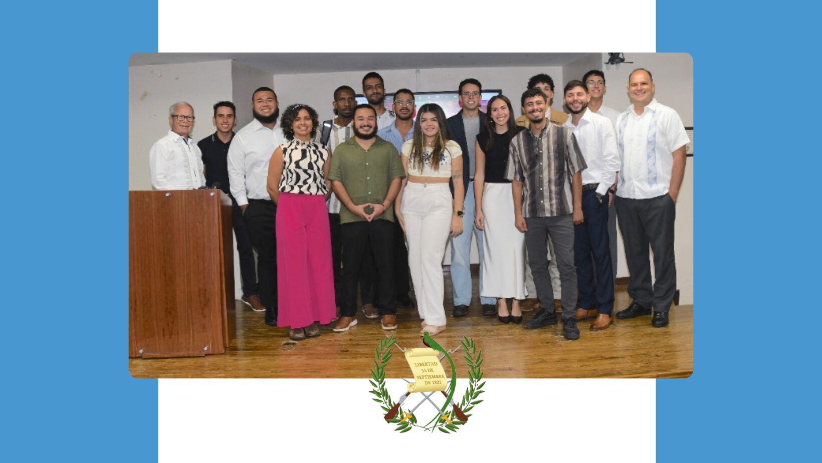 Foto grupal de los estudiantes y profesores del Colegio de Ciencias Agrícolas del RUM, que participaron en el viaje de estudio a Guatemala. Todos de pie, en el escenario del anfiteatro de Empresas. De fondo, un arte con la bandera de Guatemala.