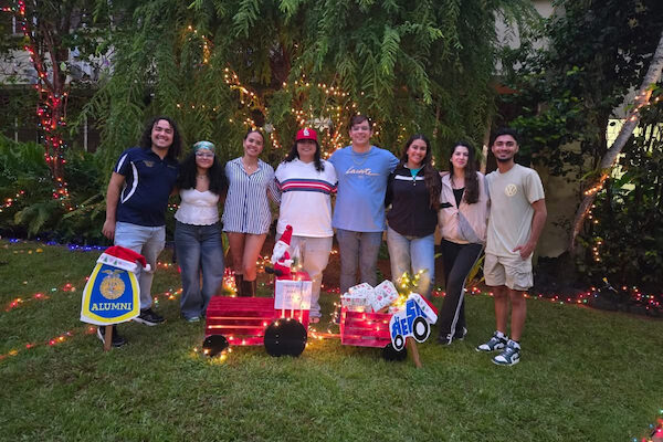 Grupo de estudiantes posa de pie en el patio interior del edificio Piñero durante su encendido navideño.