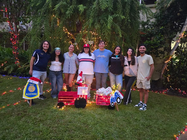 Grupo de estudiantes posa de pie en el patio interior del edificio Piñero durante su encendido navideño.
