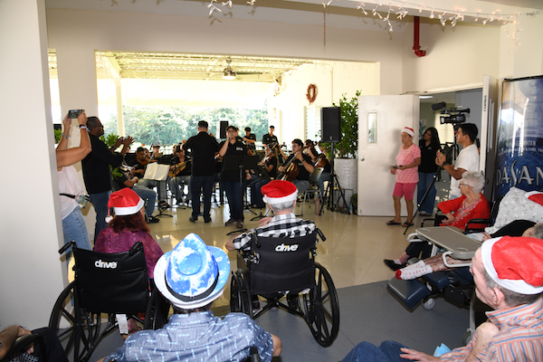 La música se convirtió en un regalo de esperanza y compañía cuando la Orquesta de Cuerdas del Recinto Universitario de Mayagüez (RUM) visitó el Hogar Casa Linda, en el barrio Cuba de Mayagüez, para ofrecer un concierto navideño que llenó de sonrisas a los residentes y al personal del centro.
La presentación forma parte de los esfuerzos de proyección comunitaria que impulsa el Departamento de Banda y Orquesta del RUM, con el propósito de fortalecer vínculos y compartir el arte universitario con la comunidad. Así lo explicó el doctor Santos Torres Toro, director de la agrupación.