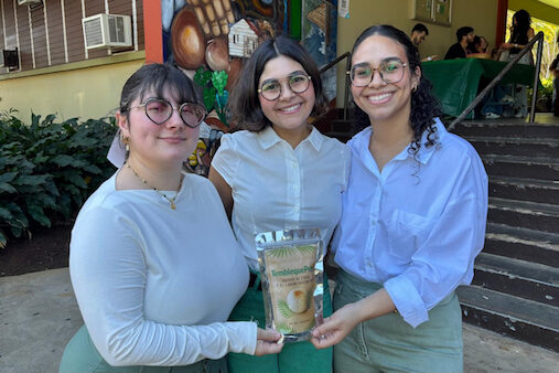 Las estudiantes de maestría en Ciencia y Tecnología de Alimentos: Alexandra Shields Cruz, Nancelys M. Rodríguez Oquendo y Nicole Rodríguez Trujillo obtuvieron el Primer lugar del curso CITA 6603 y el Premio de Innovación, originalidad y mejor presentación, por sus Tembleque Pops, en la más reciente edición de la Competencia de productos nuevos. Las tres de pie frente al edificio Piñero posan con su producto.