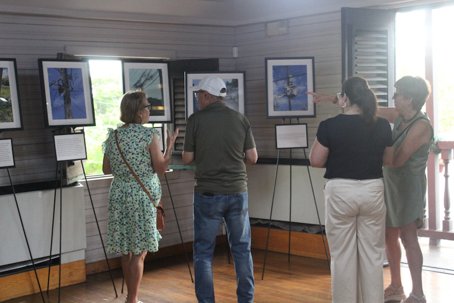 Grupo de personas observan las fotos de la exposición colocadas en trípodes.