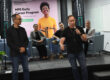 Panel de ejecutivos de la multinacional HPE en su visita al RUM, algunos de pie al frente y otros sentados en sillas, en el podio se dirigen a la audiencia.