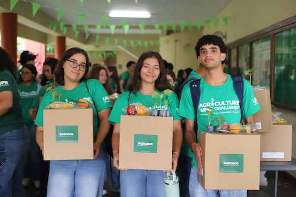 Portada Tres estudiantes del campamento Agriculture Week Challenge de pie sostienen sus cajas Agrobox con experimentos relacionados a la agricultura.