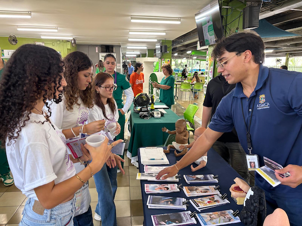 Portada La Oficina de Calidad de Vida del Recinto Universitario de Mayagüez celebró la Feria de bienestar y salud mental. Portavoces de la Administración de Salud Mental y Contra la Adicción (ASSMCA) conversan con estudiantes en su mesa de información.