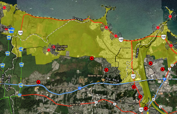 This is an image of Toa Baja from the interactive Map Tool. It is a satellite image with an overlay of the yellow evacuation zone and key symbols such as assembly points, evacuation routes, and major roads.